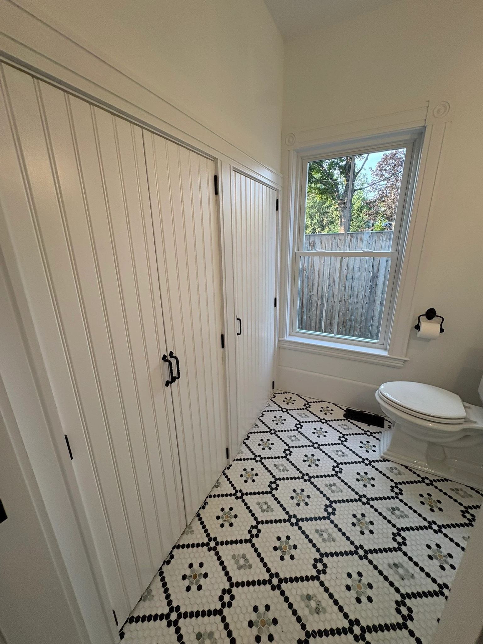 Powder room with beadboard closets over patterned hex tile